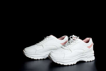 White womna's sneakers on black background.