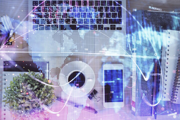 Double exposure of business theme hologram over desktop with phone. Top view. Mobile international...
