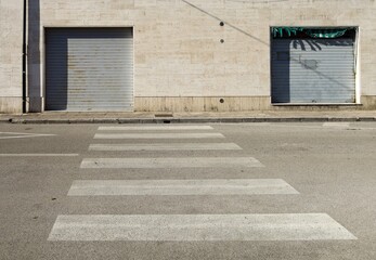 Closed city store with the shutters down. Street and crosswalk lines in front. Background for copy...