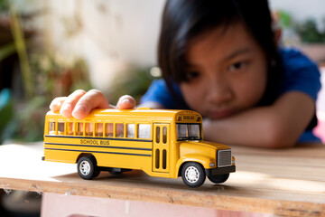 Asian child girls lonely play the yellow toy school bus during their break from school or at home. , Concept Learn at home to stop the transmission of the coronavirus or covid-19