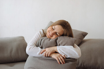 Young woman relaxing on the couch and embracing pillow at home.