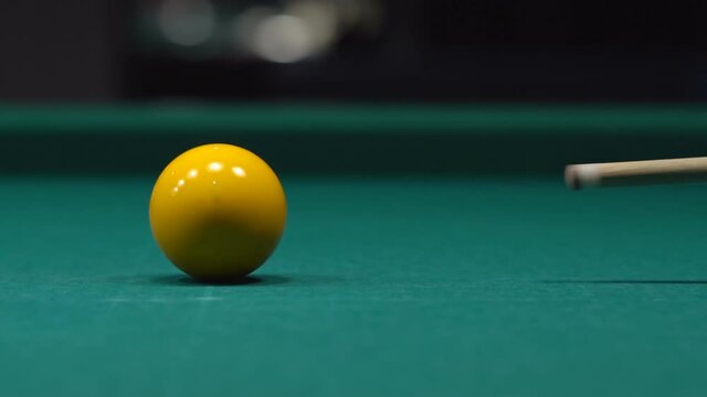 Close up of a man hits the yellow ball with a cue. Playing Billiards on the green table.