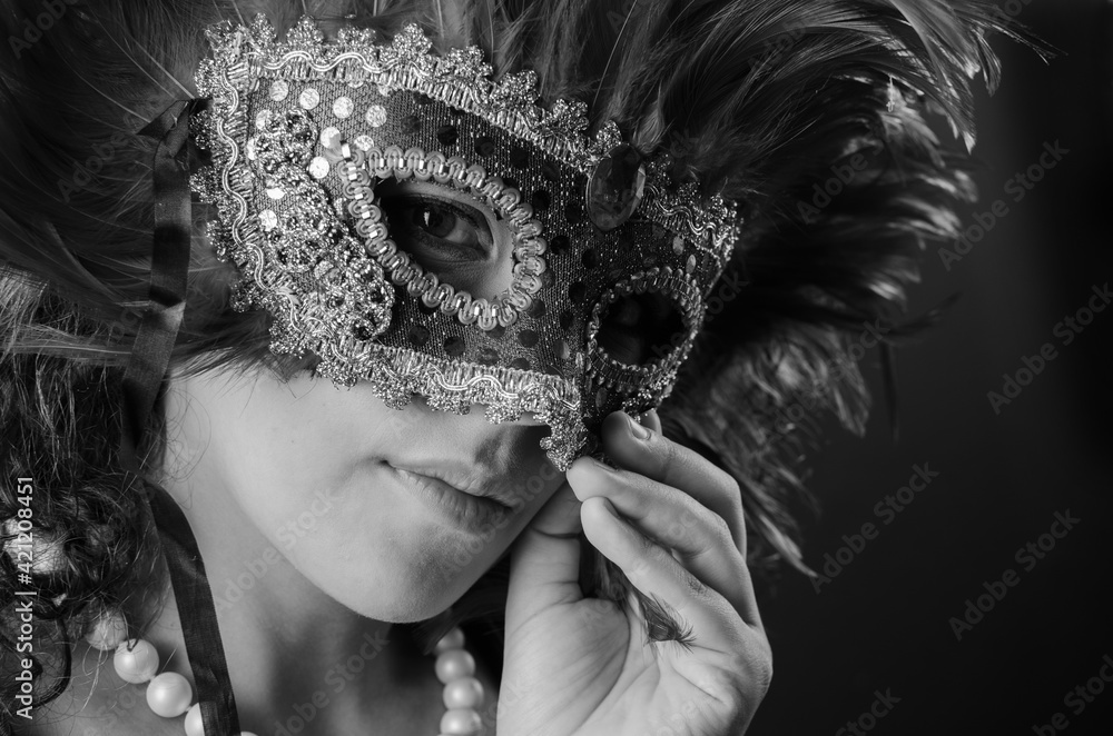 Wall mural Beautiful young Brazilian woman with brown hair wearing a Venetian mask, dark background, selective focus.