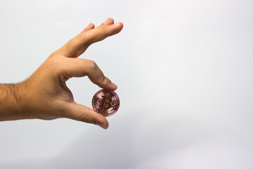 Hand holds physical bitcoin coin. Bitcoin in hand on white background. Bitcoin cryptocurrency on white canvas