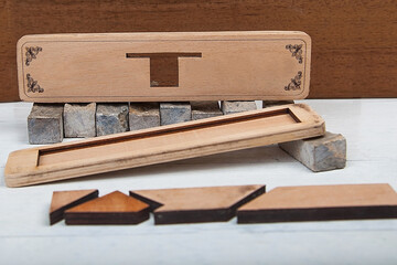 Tangram puzzle as arrow in square shape on wooden background