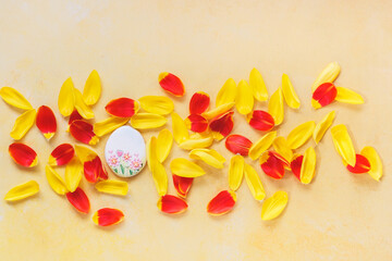 Easter composition on yellow  background. Easter egg sugar cookie and yellow  and red petal background. Top view, blank space