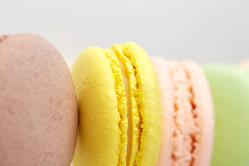 Close up photo of macaroon. Colorful cakes macaron with pastel tones laid out in a strip on white background. Focus on yellow one. Top view of almond cookies.