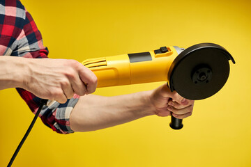 Modern, compact yellow angle grinder isolated on yellow background