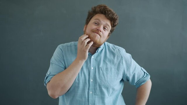 Slow motion portrait of creative young man thinking raising finger having idea standing on gray background alone and looking at camera. People and gestures concept.