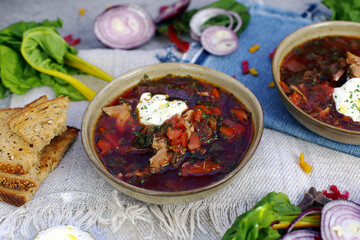 sopa de beterraba com frango derramado em pratos está na mesa em uma composição com cebola roxa...