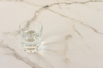 Glass with fresh water on marble table. Space for text