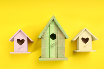 Beautiful bird houses on yellow background, flat lay