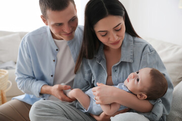 Happy family with cute baby on sofa at home