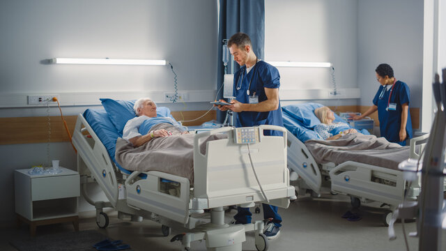 Hospital Ward: Friendly Male Nurse Talks Reassuringly to Elderly Patient Resting in Bed. Doctor Uses Tablet Computer, Does Checkup, Explains Analysis, Old Man Recovering after Successful Surgery 