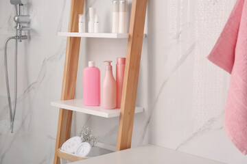 Fototapeta na wymiar Soft towels and different toiletries on decorative ladder in bathroom. Interior design
