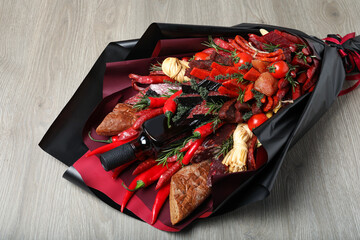 Beautiful edible bouquet with meat, cheese and vegetables on wooden table, closeup