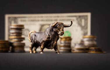 Bull in front of dollar banknote and stacks of coins, concept of strong economy and business growth