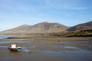Trefor beach, Wales. Two small fishing boats at a secluded bay near Snowdonia on the Llyn Peninsula on a sunny, bright spring day. Peaceful placid countryside. Landscape aspect. Clear blue sky.