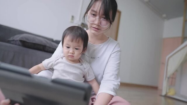 Enjoyable mother and smart infant watching online educational kid channel on tablet, Young adult mother teaching her daughter to respond a question, cute baby girl nodded her head for answering