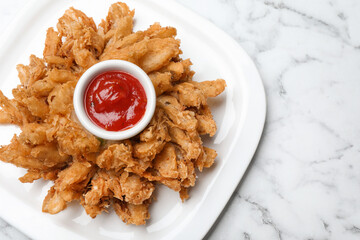 Fried blooming onion with dipping sauce served on white marble table, top view. Space for text