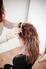 Fototapeta premium the hairdresser puts the girl's hair, jewelry made of pearls