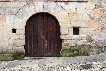 Fototapeta na wymiar Portón de madera antiguo en fachada con sillares de piedra