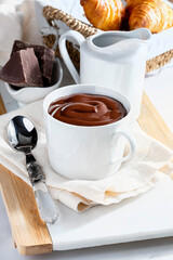 Appetizing breakfast with a delicious cup of thick, drinkable hot chocolate, along with croissants. Homemade look.