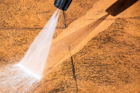 Cleaning backyard paving tiles with pressure washer cleaner.