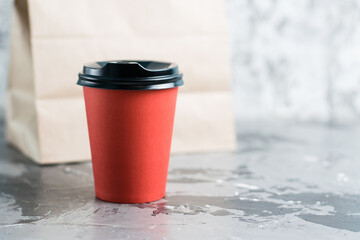 Paper cup and craft takeaway bag on gray background copy space. Concept for the development of the restaurant business and food delivery during quarantine covid 19
