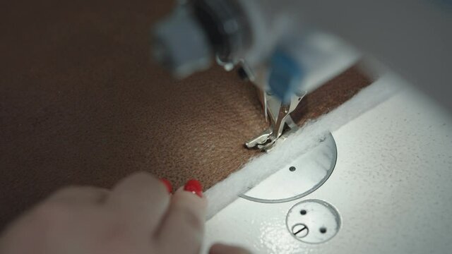 Top view of sewing process on professional sewing machine in upholstered furniture repair workshop