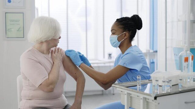 Senior women processing vaccination procedure in private clinic hospital. Professional doctor doing vaccine injection against coronavirus. Concept of health care, vaccination program