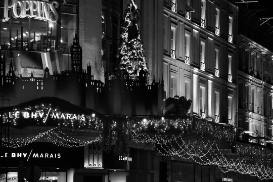 PARIS, FRANCE - DECEMBER 2, 2018:  Christmas in Paris. Night view of Christmas decoration of BHV department store at Rivoli street. Holidays shopping. Illuminated facade. Black white photo.