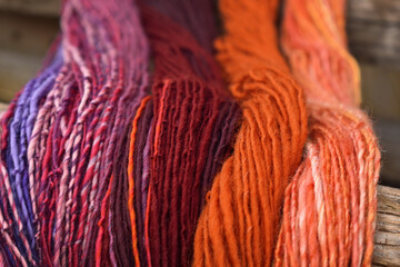 Stränge von bunter Wolle in lila, weinrot, rosa, orange hängen zum Trocknen als Hintergrund