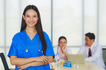 Portrait young Asian female doctor smiling with background of a senior male doctor, a young female doctor are meeting in a meeting room in the hospital.