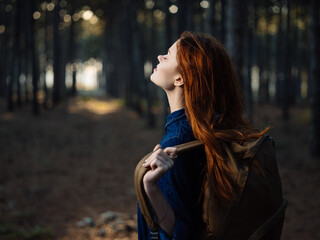 Happy traveler with a backpack on her back is resting in nature in a pine forest