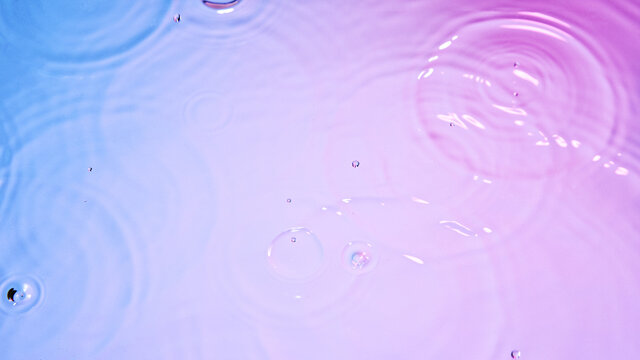 Water drops falling on neon water surface - Powered by Adobe