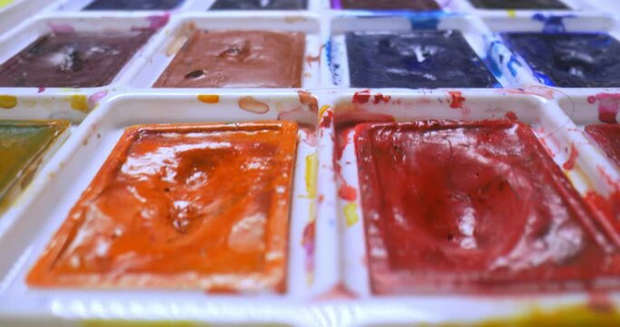 detailed extreme close-up of used art watercolors in container.