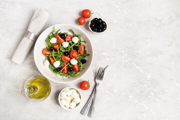 Fototapeta na wymiar Lunch in Italian restaurant. mediterranean diet food salad with arugula mozzarella tomatoes and olives, olive oil and fresh bread 