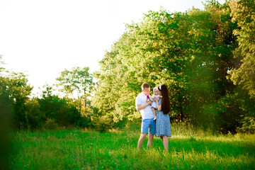 Fototapeta premium Happy family: mother father and child daughter in the park on sunset