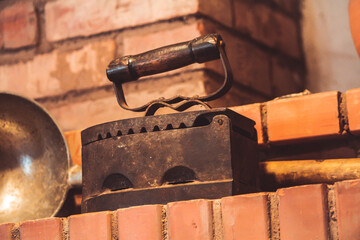 Vintage cast iron charcoal iron standing on brick wall 