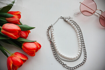 pearl jewelry and chains for girls and red tulips on a white background