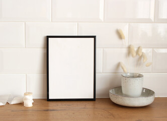 Closeup of kitchen interior. White brick wall, metro tiles, wooden table. Modern ceramic vase with dry Lagurus ovatus grass, ribbon. Modern Scandinavian design. Scandinavian interior, home design.