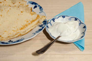 Pancakes on a plate with sour cream. Maslenitsa,
  baking pancakes
