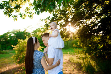 Fototapeta premium Happy family in the park evening light. The lights of a sun.
