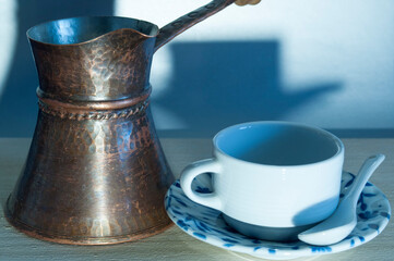 Close-up of a coffee pot and a small coffee cup on a saucer. Background.