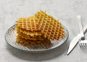 stack of baked Belgian waffles on a round plate on a white table