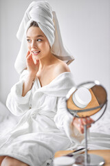 Obraz na płótnie Canvas Young woman in white towel chilling in bedroom and looking at side, going to do beauty procedures