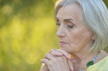 Portrait of sad senior beautiful woman in park