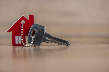 Key and house shaped keychain arrangement on wood background. Real estate, insurance concept,...