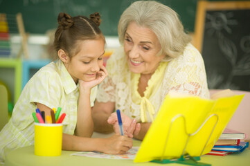 Little girl doing homework with her grandmother at home